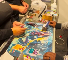 Collectors opening trading card packs on the shop counter